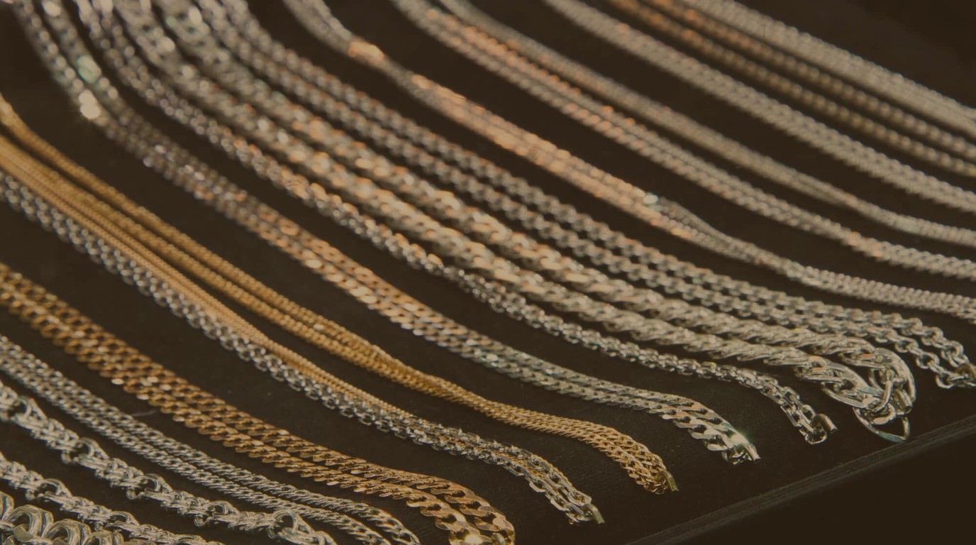 Rows of silver and gold necklace chains in many different link styles laid out on a display tray
