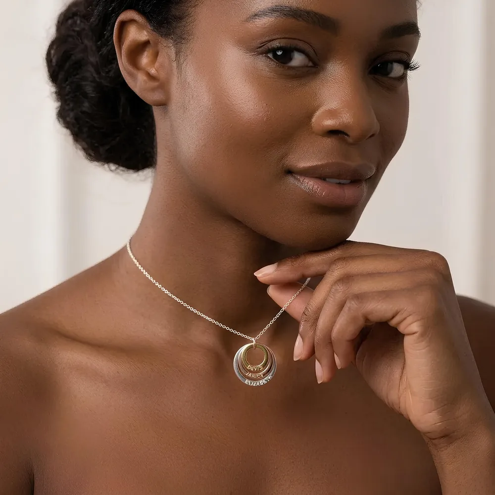 Woman resting her chin on her hand, wearing a necklace with three nested name rings engraved with her children's names