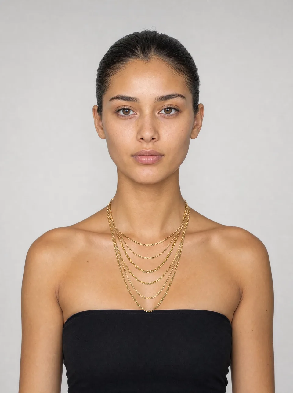A woman wearing all six chain lengths at once, from 14 inches at the base of her neck down to 24 inches at her neckline.